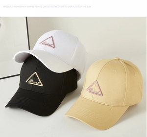 Detailed view of baseball caps in white, black, and khaki with triangular embroidery