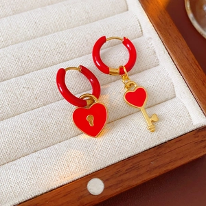 Detail shot of asymmetric red enamel heart lock and gold key earrings in a luxury jewelry box