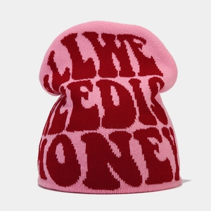 Close-up of pink knit beanie showing red jacquard lettering and soft thick texture