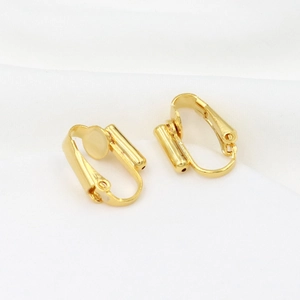 Macro detail of 18K gold plated clip-on earring converters on white fabric