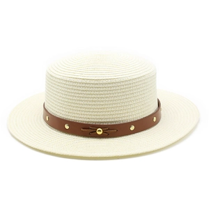 Détail du chapeau canotier crème avec ruban en cuir marron et clous dorés