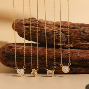 Detail of four gold zircon necklaces with heart, pear, rectangle and round cut pendants