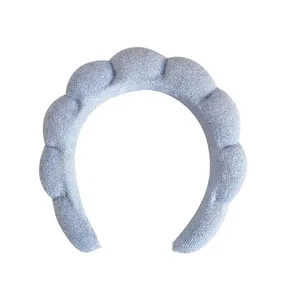 Close-up of light blue braided sponge headband with textured terry cloth and handmade label