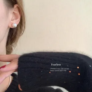 Close-up of elegant 10mm white pearl stud earring on model for a vintage aesthetic