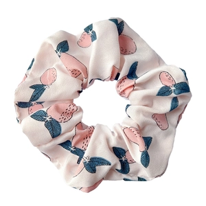 Close-up of a pink strawberry pattern scrunchie with ruffled texture on white background