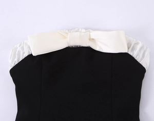 Detail of elegant black tube top featuring a large white satin bow on the neckline