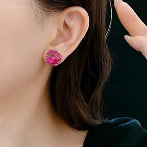 Close-up of a pink round crystal stud earring with sparkling diamond halo on a model
