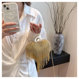 Close-up of golden heart-shaped evening bag with sparkling rhinestones and long tassels