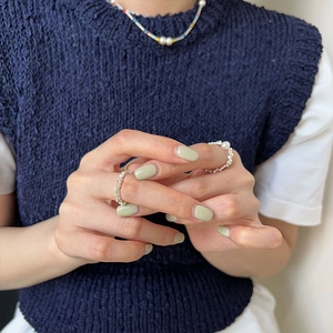 Detail shot of a layered silver bead and pearl ring set on model's hand