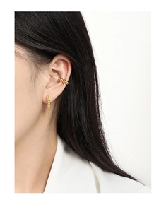 Detail of gold beaded ear cuff and round ball earring set worn by a female model