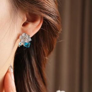 Macro side view of elegant blue flower earrings with square drop crystal on model