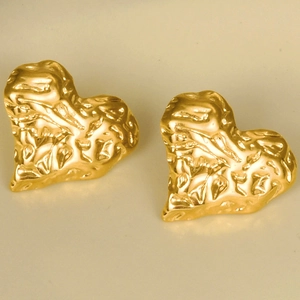 Macro view of golden heart-shaped stud earrings with unique irregular hammered texture