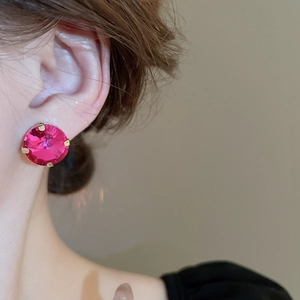 Close-up of pink round gemstone stud earrings in gold four-prong setting on a model