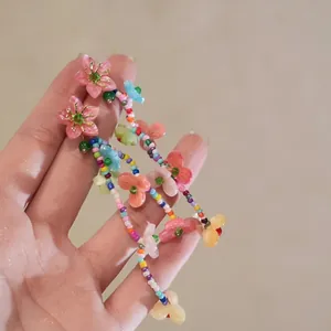 Detail of colorful beaded long earrings with multi-color beads and floral pendants