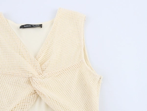 Nahaufnahme der V-Ausschnitt-Strickkleid-Details mit Netz-Hohlstruktur und Knotendesign
