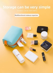 Hemelblauwe PU-make-uptas met oranje handvat en cosmetica op een gele achtergrond