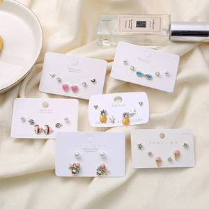Close-up of colorful summer-themed earrings like hearts and shells on a textured fabric