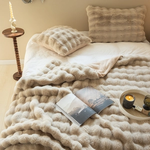 Close-up of beige faux rabbit fur blanket and matching pillow with soft striped texture