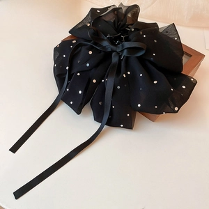 Détail d'une grande pince à cheveux avec nœud en résille noire, pois argentés et rubans