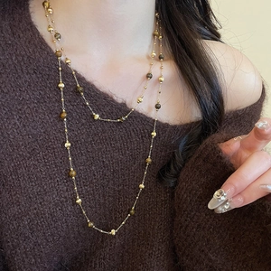 Detail of 18k gold plated necklace with tiger eye and pearls on a brown sweater