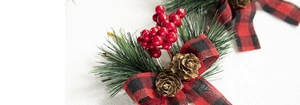 Macro detail of Christmas decoration with red berries, pine cones and plaid ribbon