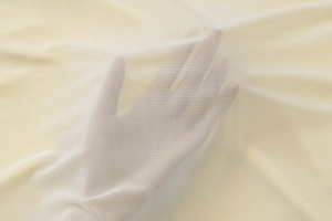 Close-up of beige mesh fabric texture showing sheer transparency and breathable knit
