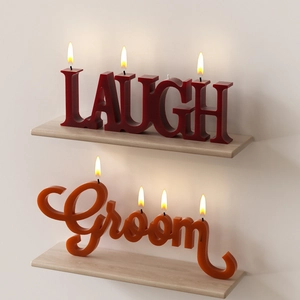 Artistic word candles LAUGH and Groom on a wooden shelf with a warm glowing flame