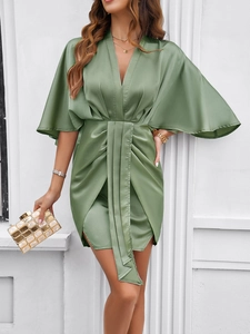 Detail of green satin dress featuring a deep V-neck and elegant waist pleats