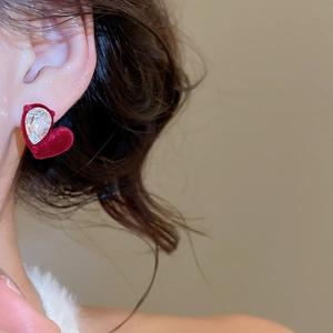 Detail of a red velvet heart earring with a teardrop zircon on a model's ear