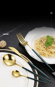 Detailed macro view of luxury gold and matte green stainless steel cutlery set on marble