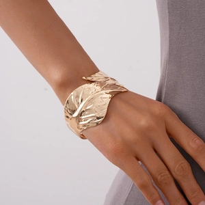 Detail of a golden leaf-shaped open cuff bracelet featuring realistic vein textures