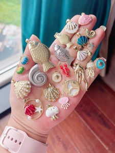 Vue macro de pendentifs marins en émail coloré et de breloques en laiton sur une paume