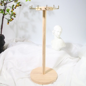 Detail of wooden jewelry stand with gold hooks and white fabric background