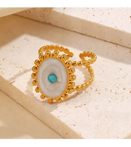 Vue macro de la bague perlée dorée avec résine blanche ovale et perle bleue turquoise