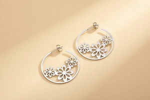 Detailed close-up of silver steel hoop earrings with delicate hollow flower patterns