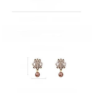 Vue détaillée de boucles d'oreilles vintage avec feuilles dorées, cristaux et perles