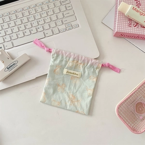 Detail view of a cute mint green drawstring pouch with orange cat prints and pink ties