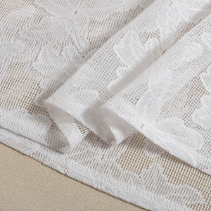 Close-up of white floral lace fabric with detailed mesh texture and jacquard pattern