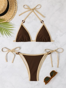 Detailed flat lay of a brown bikini set with resin rings and tropical beach accessories
