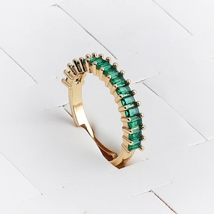 Detailed view of adjustable gold ring with square green cubic zirconia stones