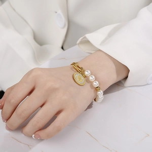 Detail of 18K gold-plated pearl bracelet with tree of life charm on model's wrist