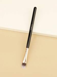 Macro detail of tongue-shaped concealer brush with rose gold ferrule and synthetic bristles