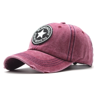 Macro detail of washed burgundy denim baseball cap with distressed star patch and embroidery