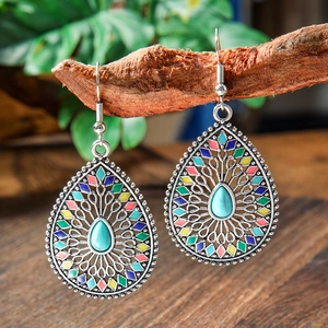 Detail of bohemian drop earrings with turquoise stone hanging on a natural wood branch