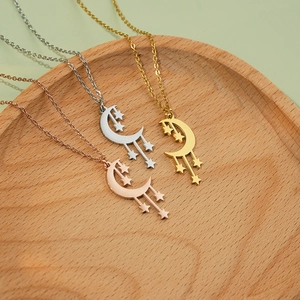 Star and moon necklace set in gold, silver, and rose gold finishes on wood tray