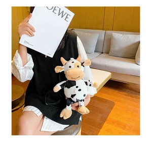 Close-up of cute cow plush crossbody bag with black and white spots and pink cheeks