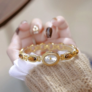 Detail of vintage gold bracelet watch for women with brown tiger eye stone inlays