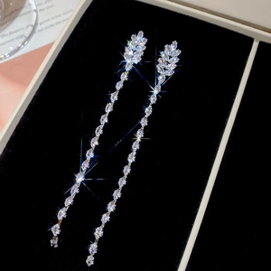 Macro view of long fringe earrings with marquise-cut zircon stones on a black velvet base