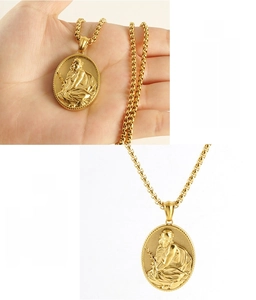 Detailed view of religious portrait pendant on box chain with hand for scale