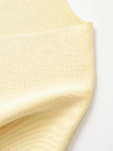 Macro shot of light yellow knit fabric showing detailed texture and soft ribbed pattern